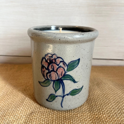                             stoneware candle crock with a hand decorated pink peony pattern outlined in cobalt blue with wispy green leaves.  Candle crock with a white shiplap background