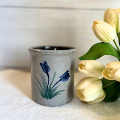                             Handcrafted Rowe Pottery spring candle crock, decorated with two tulips in cobalt blue with green stems, pictured with bouquet of spring tulips